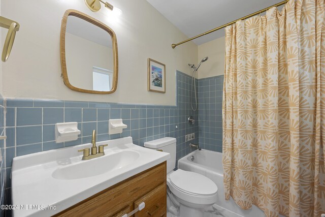 full bathroom featuring tile walls, shower / tub combo with curtain, vanity, and toilet