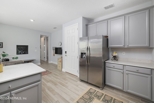 kitchen with light hardwood / wood-style floors, stainless steel refrigerator with ice dispenser, and gray cabinets