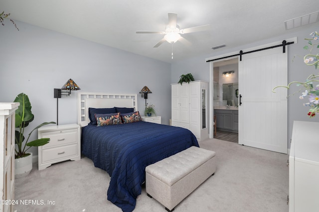 bedroom with connected bathroom, ceiling fan, light carpet, and a barn door