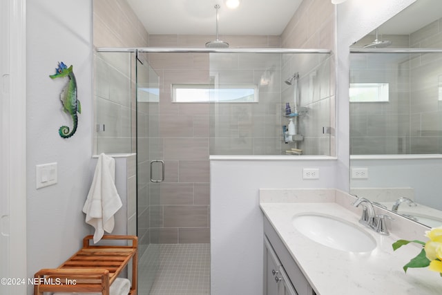 bathroom featuring vanity, a healthy amount of sunlight, and a shower with shower door