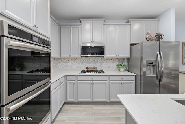 kitchen featuring appliances with stainless steel finishes, decorative backsplash, and white cabinets