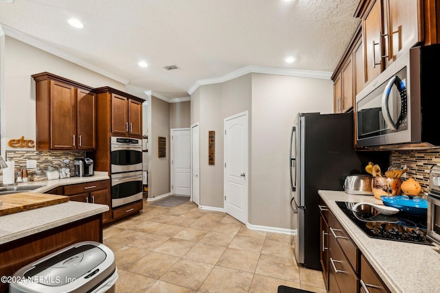 kitchen featuring decorative backsplash, crown molding, light tile patterned floors, and stainless steel appliances