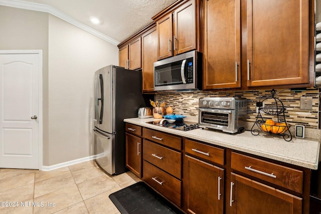 kitchen featuring light tile patterned flooring, tasteful backsplash, stainless steel appliances, a textured ceiling, and ornamental molding