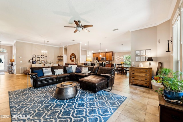 tiled living room with ceiling fan with notable chandelier and ornamental molding