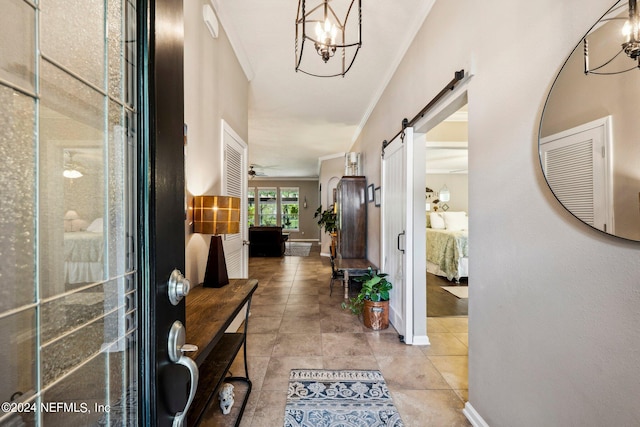 foyer featuring ceiling fan with notable chandelier, crown molding, and a barn door