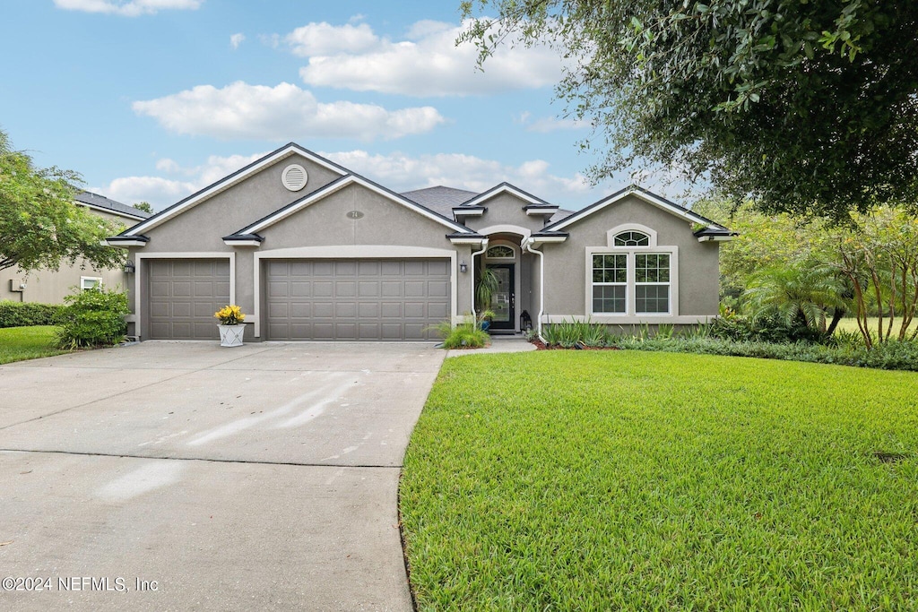 single story home featuring a front lawn and a garage