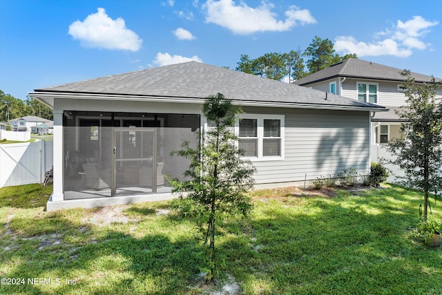 rear view of property featuring a sunroom and a yard