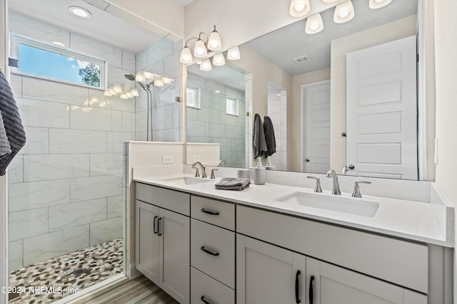 bathroom featuring wood-type flooring, vanity, and tiled shower