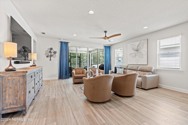 living room with light hardwood / wood-style floors, a textured ceiling, and ceiling fan