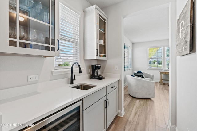 kitchen with wine cooler, light wood-type flooring, white cabinets, and plenty of natural light