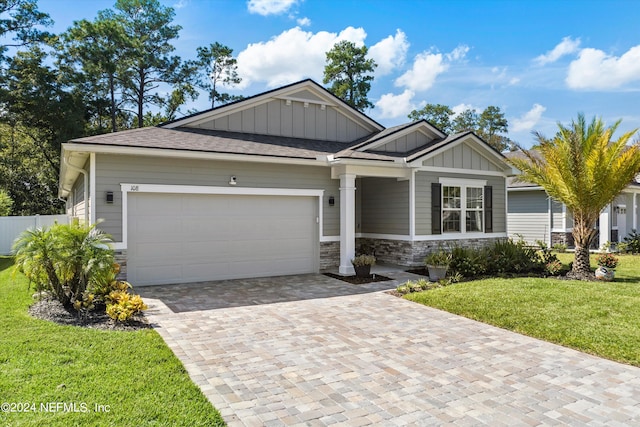 craftsman house with an attached garage, stone siding, decorative driveway, a front lawn, and board and batten siding