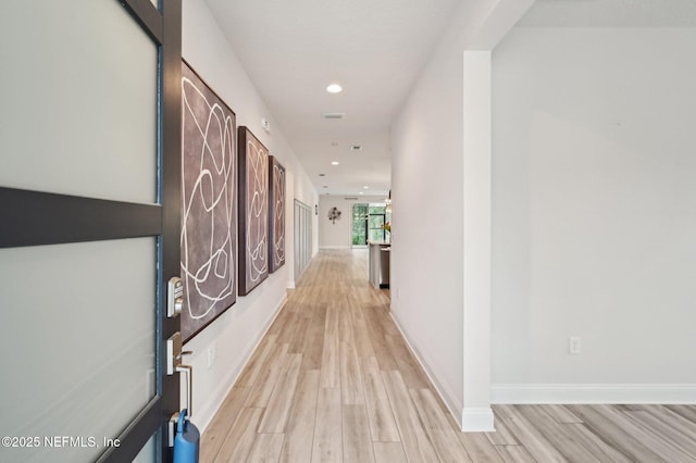 hall with light wood-style flooring, baseboards, and recessed lighting