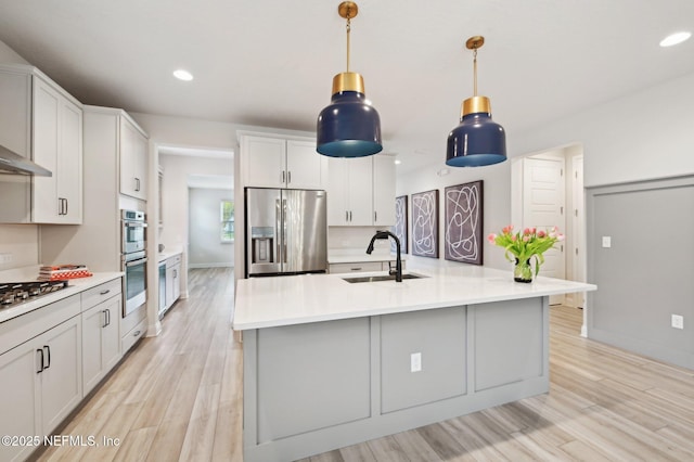 kitchen featuring stainless steel appliances, light wood-style floors, light countertops, and a sink