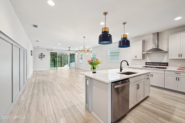 kitchen with light countertops, open floor plan, a sink, wall chimney range hood, and dishwasher