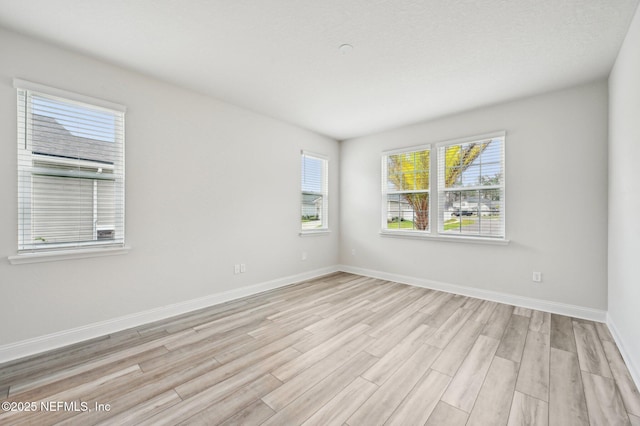 unfurnished room with baseboards and light wood finished floors