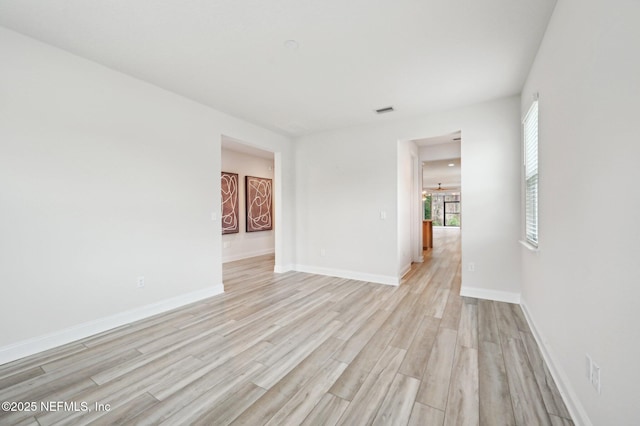 empty room featuring light wood-type flooring, visible vents, and baseboards