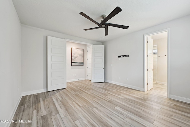 unfurnished bedroom featuring light wood-type flooring, ensuite bath, and baseboards