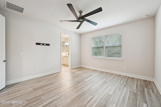 empty room featuring a ceiling fan, light wood-type flooring, visible vents, and baseboards