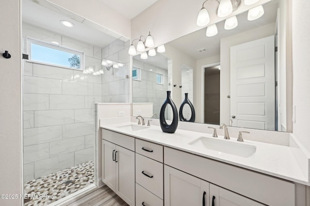 full bathroom featuring double vanity, visible vents, walk in shower, and a sink