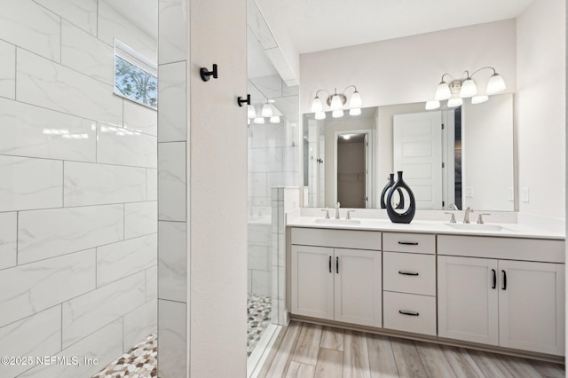 bathroom featuring a walk in shower, double vanity, wood finished floors, and a sink