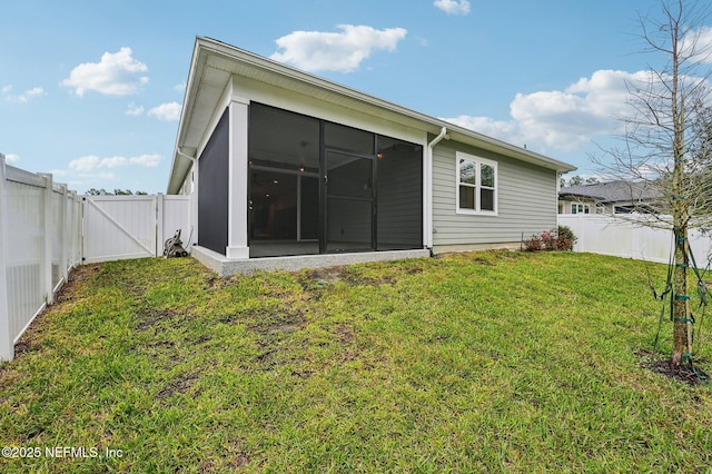 rear view of house with a sunroom, a fenced backyard, a gate, and a yard