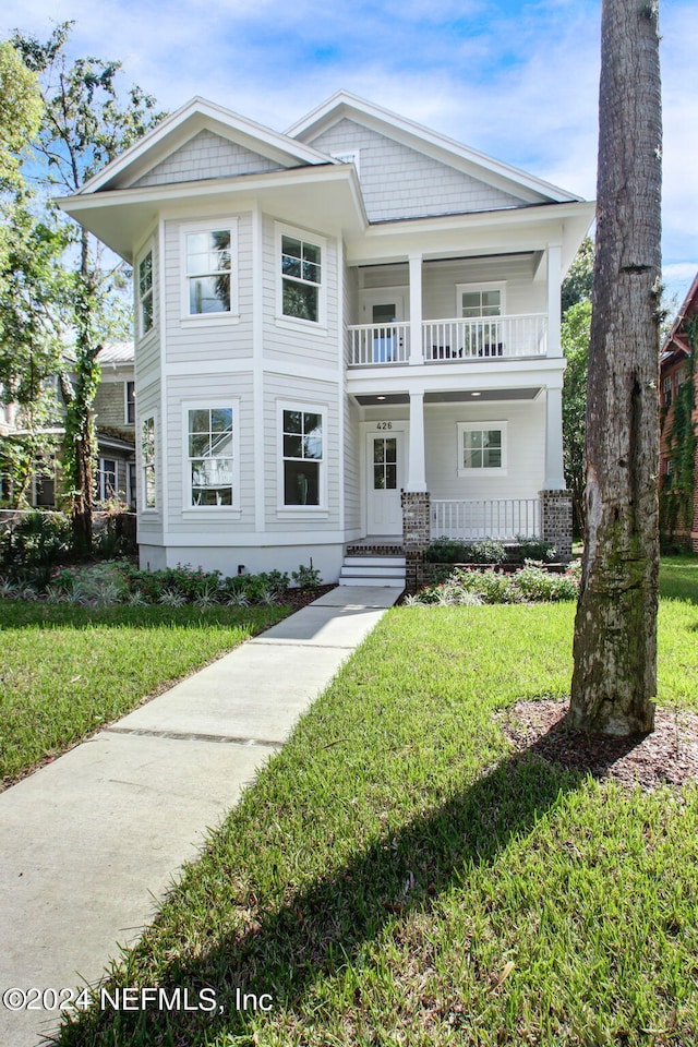 view of front of home featuring a balcony, a front lawn, and covered porch