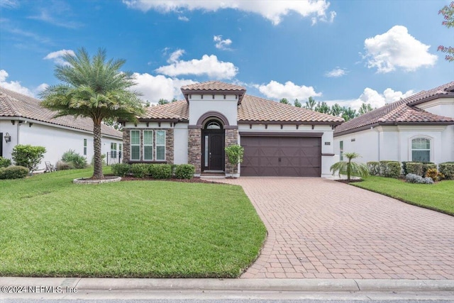 mediterranean / spanish-style home featuring a front yard and a garage