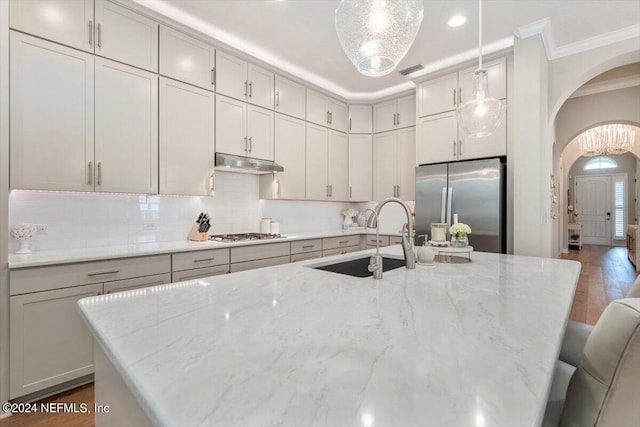 kitchen with appliances with stainless steel finishes, a center island with sink, dark hardwood / wood-style floors, and light stone counters