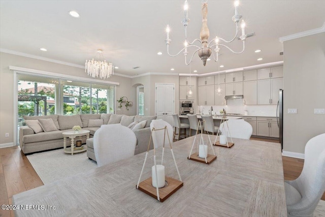 dining area with a notable chandelier, light wood-type flooring, and crown molding