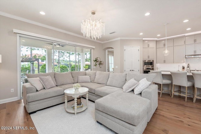 living room featuring a notable chandelier, light wood-type flooring, and crown molding