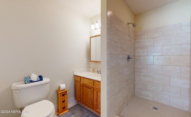 bathroom with a tile shower, vanity, and toilet