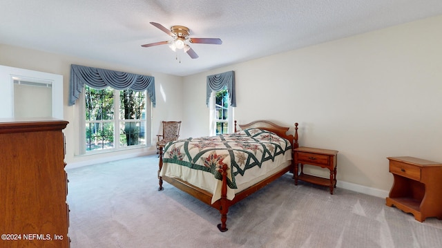 bedroom featuring a textured ceiling, ceiling fan, and light carpet