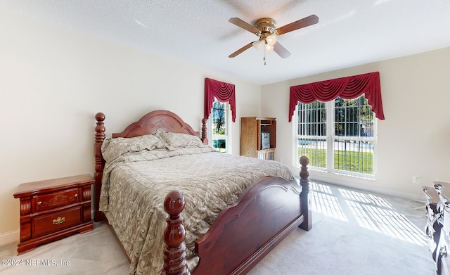 bedroom featuring ceiling fan, light colored carpet, and a textured ceiling