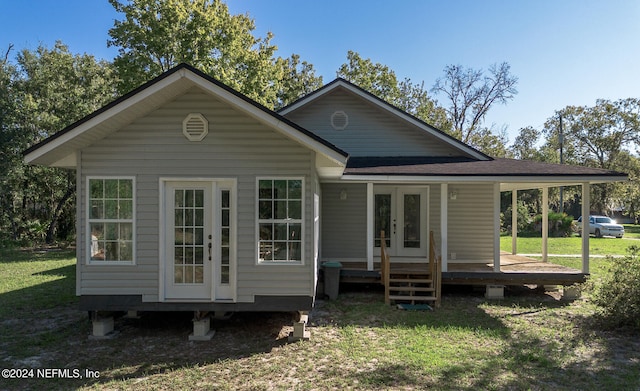 rear view of property with covered porch, french doors, and a yard