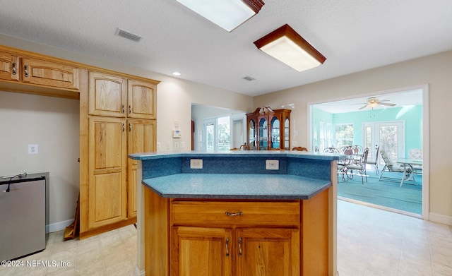 kitchen featuring ceiling fan, a center island, a textured ceiling, and french doors