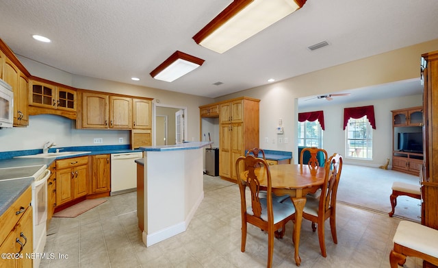 kitchen featuring ceiling fan, sink, a center island, a textured ceiling, and white appliances