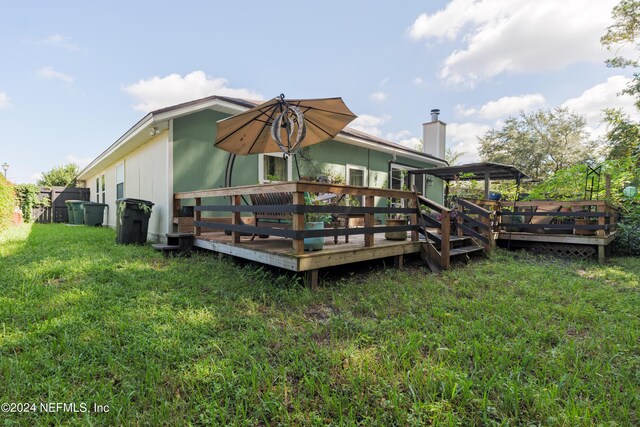 back of property with a deck and a yard