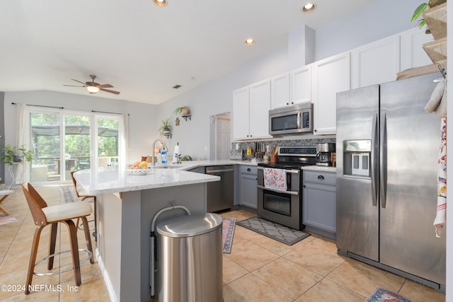 kitchen featuring ceiling fan, white cabinets, gray cabinets, appliances with stainless steel finishes, and a kitchen bar