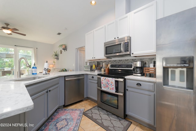 kitchen featuring gray cabinetry, decorative backsplash, stainless steel appliances, ceiling fan, and sink