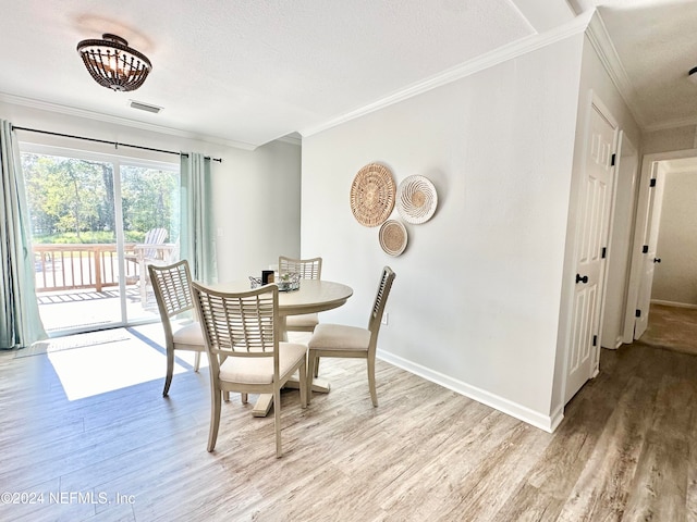 dining space with a textured ceiling, light wood-type flooring, and crown molding