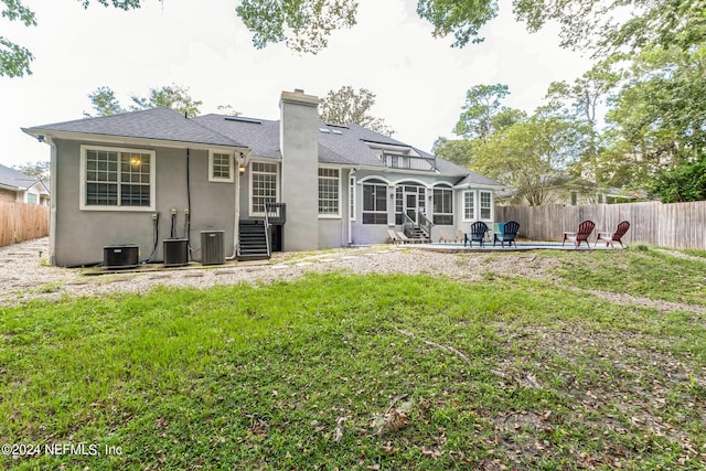 back of property with a lawn, central AC, a patio area, and an outdoor fire pit