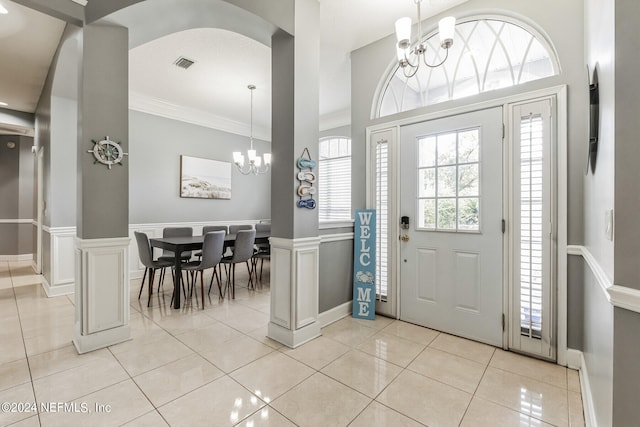 foyer with ornamental molding, a chandelier, and light tile patterned flooring