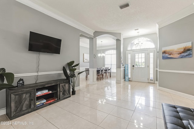 tiled entrance foyer featuring a textured ceiling, crown molding, and a chandelier