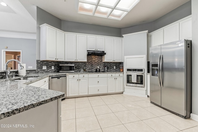 kitchen featuring appliances with stainless steel finishes, decorative backsplash, light stone countertops, and white cabinets