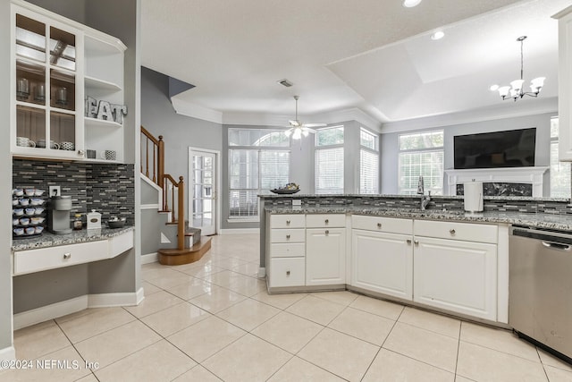 kitchen featuring dark stone countertops, tasteful backsplash, white cabinets, ceiling fan with notable chandelier, and stainless steel dishwasher