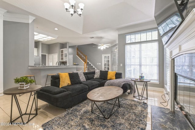 tiled living room featuring ceiling fan with notable chandelier and sink