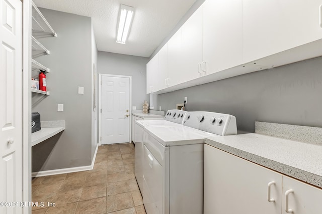 laundry area with cabinets, a textured ceiling, light tile patterned floors, and washing machine and dryer