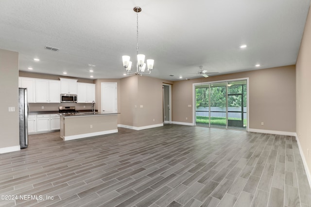 kitchen featuring appliances with stainless steel finishes, a kitchen island with sink, light hardwood / wood-style flooring, white cabinetry, and hanging light fixtures