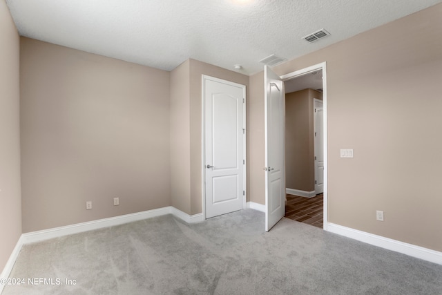 unfurnished bedroom featuring a textured ceiling and light carpet