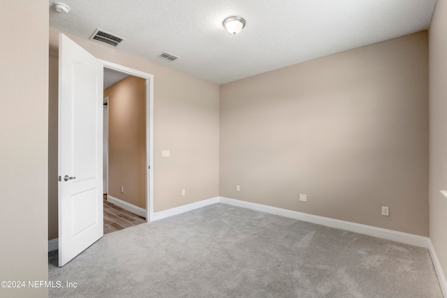 carpeted spare room featuring a textured ceiling